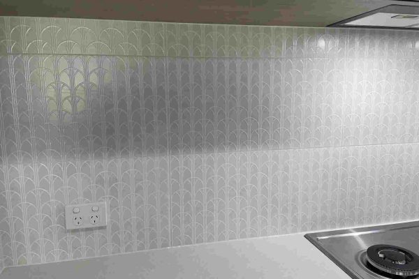 A modern kitchen in Carlingford, NSW, showcasing a decorative tile backsplash with a geometric design.